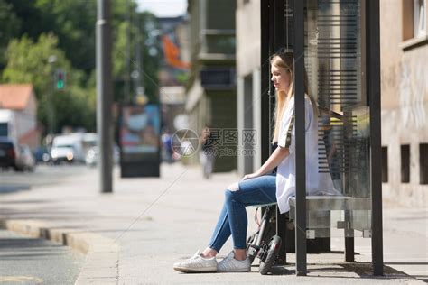 坐在公交车站点等车的年轻女孩高清图片下载-正版图片503710944-摄图网