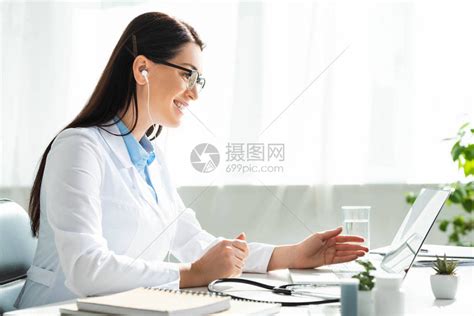 在诊所办公室用笔记本电脑与病人进行在线咨询的耳听器女医生高清图片下载-正版图片503494571-摄图网