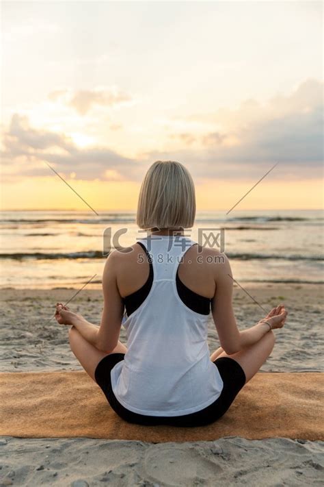 瑜伽、正念和冥想概念-日落时在海滩上以莲花姿势冥想的女人。拖鞋瑜珈高清摄影大图-千库网