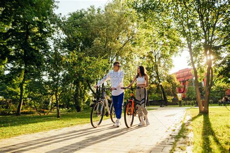 美丽的年轻夫妇男人和女人在公园的小巷里骑自行车和交流高清图片下载-正版图片506737676-摄图网
