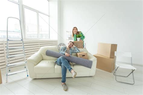 满意的快乐年轻夫妇强壮的男人和漂亮的女人手里拿着他们的东西坐在新公寓的客厅高清图片下载-正版图片506218894-摄图网