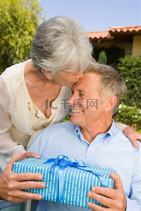 老年妇女送给丈夫生日礼物，并亲吻他的额头高清摄影大图-千库网