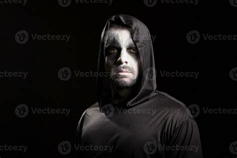 Young man looking serious into the camera dressed up like grim reaper ...