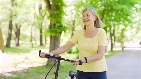 老年活跃的白发妇女在城市夏季公园户外慢跑。成熟的老年健身女性戴着耳机享受和听音乐跑步锻炼视频素材_ID:VCG42N1401048249 ...