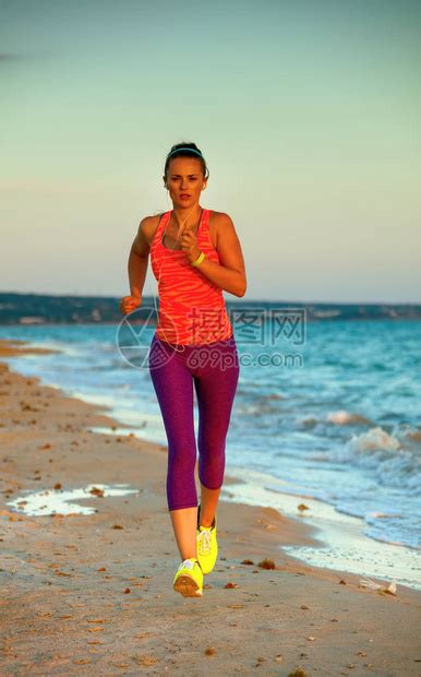 穿着运动风格服装的合适女子在晚上慢跑时在海边高清图片下载-正版图片503517698-摄图网