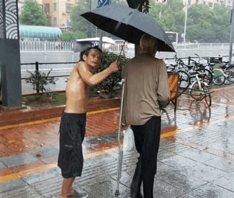 湖南长沙: 暴雨中 流浪乞丐为腿脚不便老人撑伞