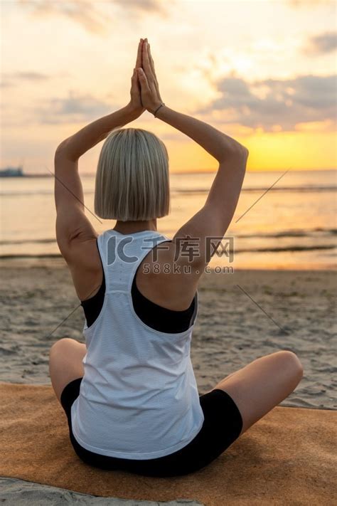 瑜伽、正念和冥想概念-日落时在海滩上以莲花姿势冥想的女人。瑜珈瑜伽高清摄影大图-千库网