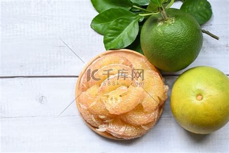 木板背景上的柚子果、新鲜的绿色柚子去皮和叶子来自柚子树、柚子、泰国夏季热带水果中的柚子高清摄影大图-千库网