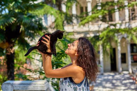 一个小女孩和她在街上捡到的一只黑猫玩耍高清摄影大图-千库网