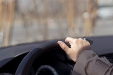 在驾驶汽车时男人手握方向盘的特写-包图企业站