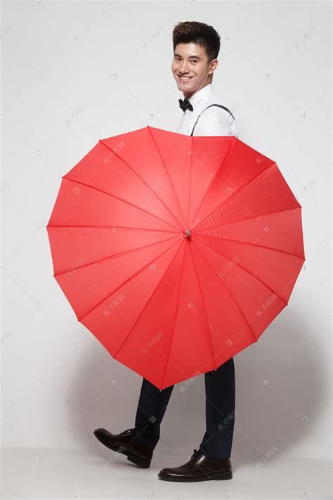 青年男人拿着心形红雨伞高清摄影大图-千库网