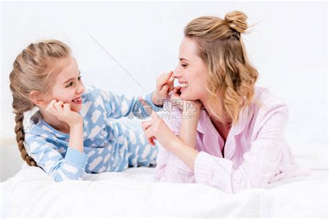 年轻活跃的母亲和她的小女孩在家穿睡衣的卧室里玩得开心高清图片下载-正版图片506651178-摄图网
