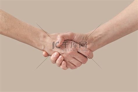 两个女人握手协议或问候手势，在米色背景中孤立的朋友的帮助手上签名。两个女人在米色上握手。高清摄影大图-千库网