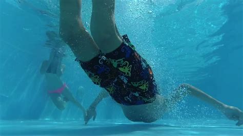 快乐男孩跳进游泳池，在水下游泳，户外视频素材_ID:VCG42N1077600676-VCG.COM