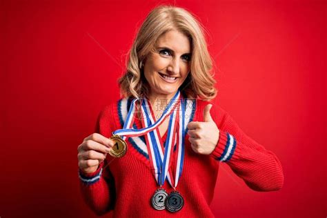 中年美丽的金发成功女在红色背景中赢得奖牌高清图片下载-正版图片504229258-摄图网