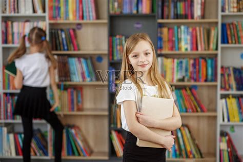 孩子在书店买书学习或阅读。女孩在学校图书馆选书。照片摄影图片_ID:441114211-Veer图库
