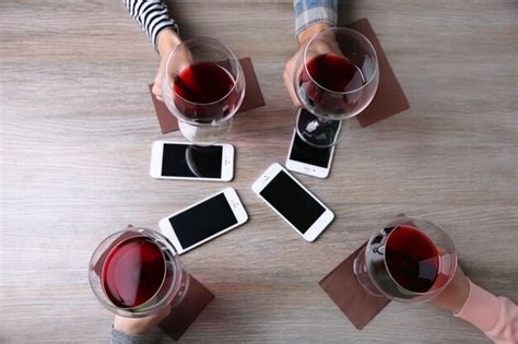 Premium Photo | Four hands with smart phones holding glasses with red ...
