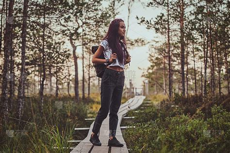一个瘦骨嶙峋的女人在茂密的松林中间的小路上徒步行走。