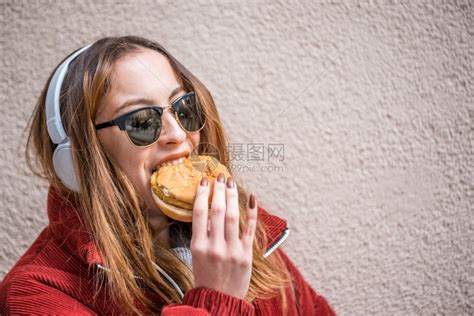 穿时装的漂亮可爱女孩喜欢吃快餐汉堡却站在墙前高清图片下载-正版图片307208116-摄图网