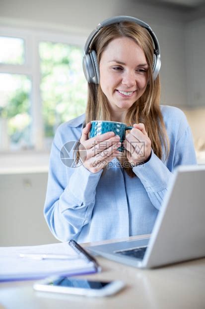 女士垂直的利用笔记本电脑和戴耳机在家学习的妇女距离高清图片下载-正版图片307778297-摄图网