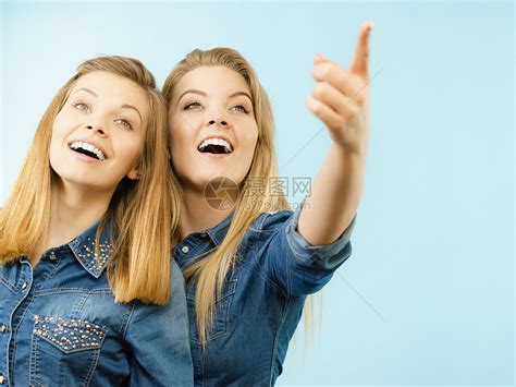 友谊,人际关系两个快乐的女朋友姐妹穿着牛仔裤衬衫指着某个地方两个快乐的女朋友穿着牛仔裤的衣服高清图片下载-正版图片300882726-摄图网