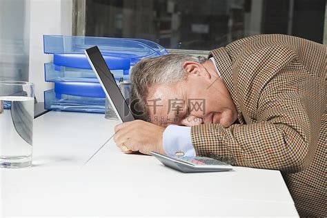 侧面的精疲力竭的商人与头在笔记本电脑在办公室高清摄影大图-千库网