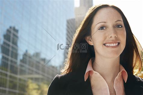 一位面带微笑的年轻女商人在办公楼前的特写高清摄影大图-千库网
