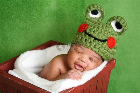 十三天大的微笑新生男婴戴着一顶绿色钩编青蛙帽他睡在一个红色的木箱里在工作室拍摄的绿色高清图片下载-正版图片503216488-摄图网