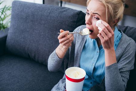 悲伤的女子吃冰淇淋而在家独自坐在沙发上高清图片下载-正版图片503364012-摄图网