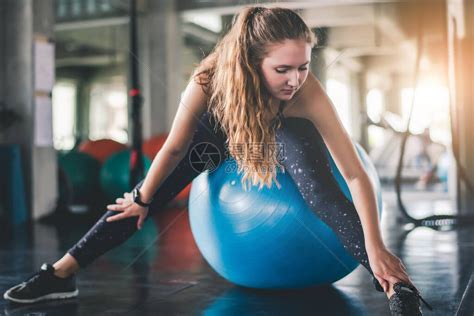 年轻有吸引力的健身女子在健身房里用球进行锻炼高清图片下载-正版图片506680341-摄图网