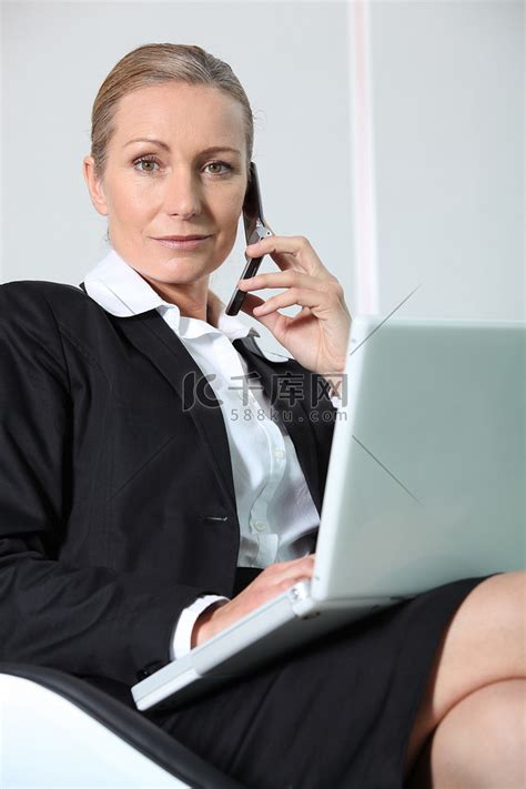 拿着笔记本电脑打电话的女商人。高清摄影大图-千库网
