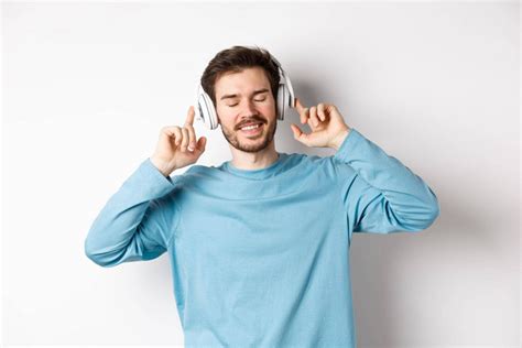 英俊的男人听音乐无线耳机微笑享受好声音白-包图企业站