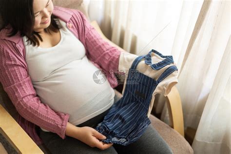 孕妇展示自己给孩子买的婴儿服高清图片下载-正版图片302551605-摄图网