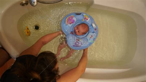 母亲在儿童救生圈中为刚出生的女孩洗澡一个月大的婴儿第一次在水高清图片下载-正版图片506490226-摄图网