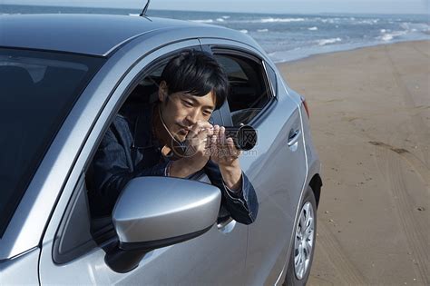 一个男人在海滩边拍照高清图片下载-正版图片502021248-摄图网