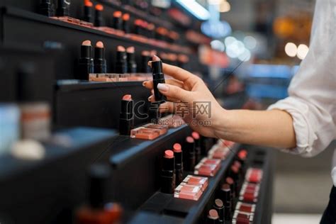 女人从化妆品店的货架上拿口红。键盘台式电脑高清摄影大图-千库网