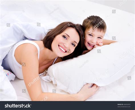 Happy Cheerful Mother And Her Pretty Son Lying On A Bed Stock Photo ...