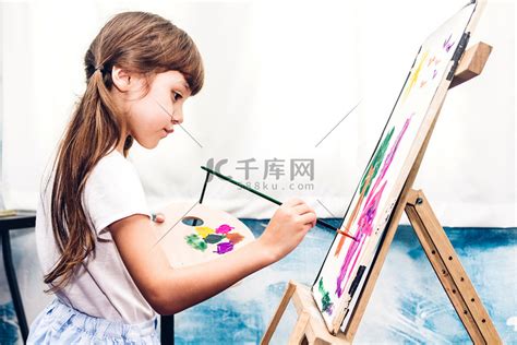 小女孩画家在画布上画画，家里有彩色调色板和水彩画高清摄影大图-千库网
