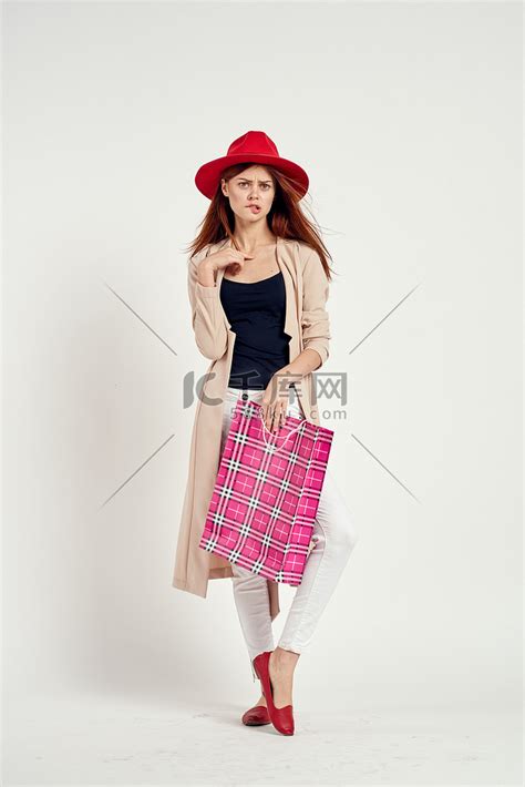 戴着红帽子的漂亮女人摆出购物乐趣的孤立背景高清摄影大图-千库网