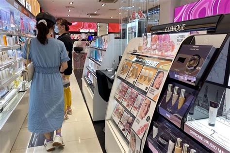 销售、购物和化妆概念-快乐的女售货员或化妆师在化妆品店背景上涂上口红。高清摄影大图-千库网