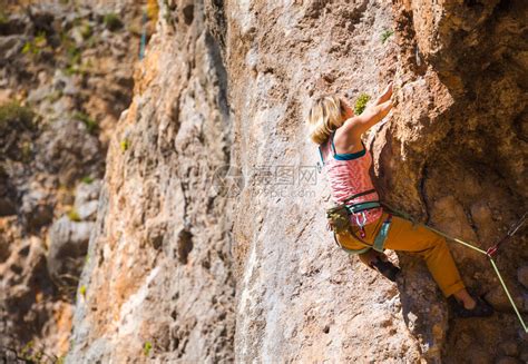 一个女孩爬上岩石运动员在大自然中训练女人克服了艰难的攀登路线强壮的登山者极端的爱好高清图片下载-正版图片506587701-摄图网