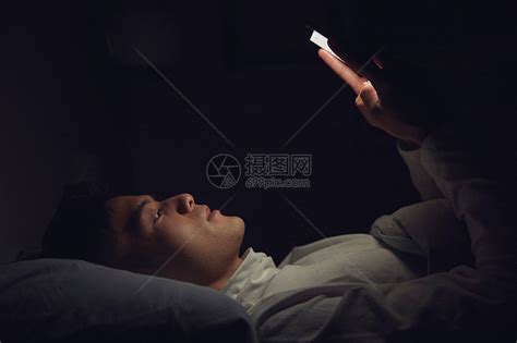 年轻男士深夜躺在床上玩手机高清图片下载-正版图片501687443-摄图网