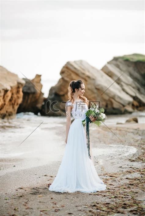 在夕阳的黑海岸边，新娘带着婚礼花束高清摄影大图-千库网