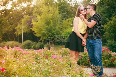 爱与幸福约会年轻一对牵手情侣在外边的花公园里玩得开心男人亲吻女高清图片下载-正版图片305075040-摄图网
