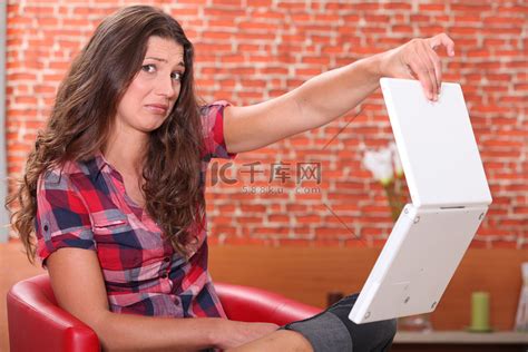 女人轻蔑地拿着她的笔记本电脑高清摄影大图-千库网