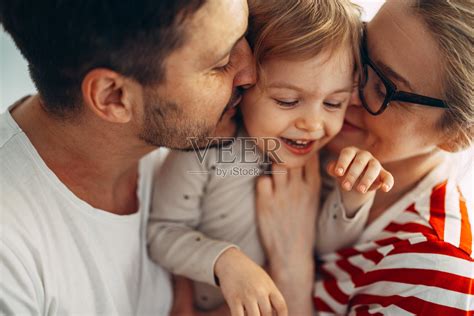 一对幸福的夫妇和他们的女儿在家里拥抱的肖像照片摄影图片_ID:425731642-Veer图库