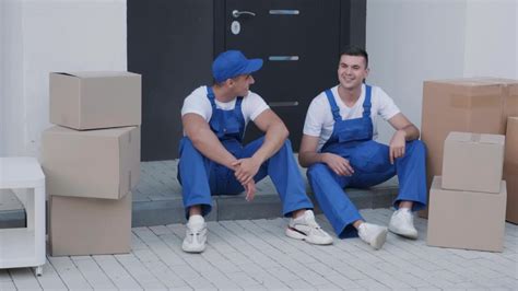 两个搬家公司的年轻工人正在把箱子和家具装上一辆小巴视频素材_ID:VCG42N1390330560-VCG.COM