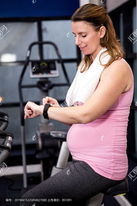 孕妇骑自行车在健身房看她的手表,摄影素材,汇图网www.huitu.com