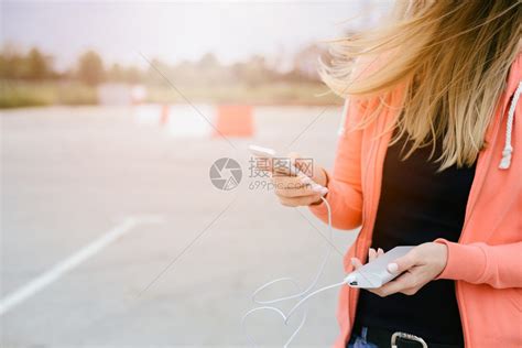有电话和移动电源的女人玩智能手机游戏在街上用智能手机玩手高清图片下载-正版图片502894988-摄图网