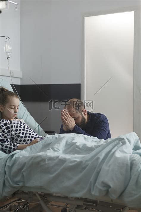 忧心忡忡的父亲为躺在病床上的生病女儿祈祷高清摄影大图-千库网